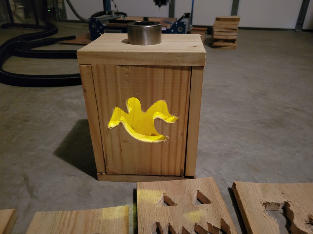 Unfinished cedar Halloween lantern box with a glowing ghost face and solar light stem