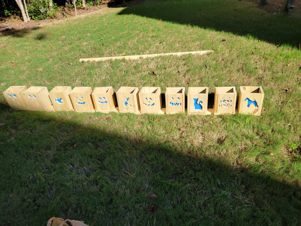 Lineup of assembled cedar Halloween lantern boxes outdoors before final finishing