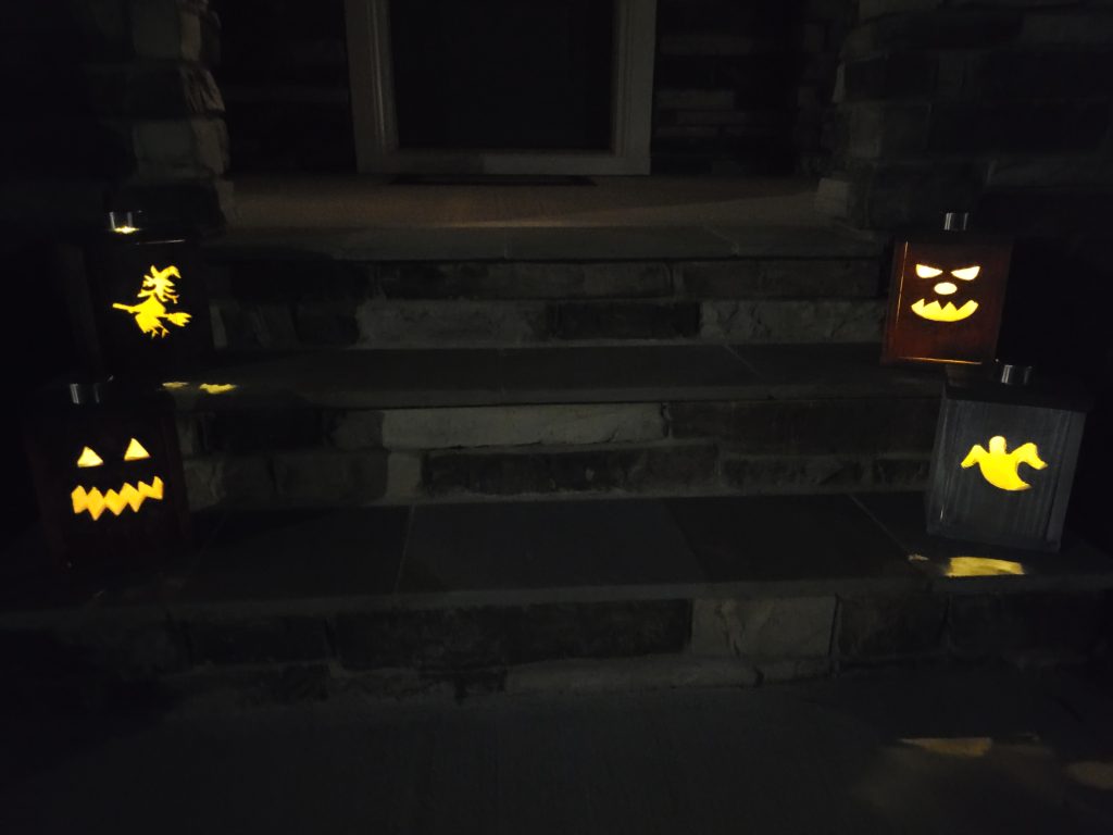 Halloween lantern boxes glowing at dusk on the front steps with solar lights as stems