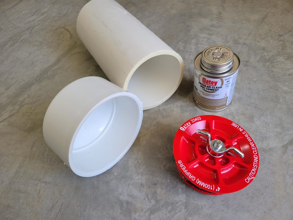 PVC pipe, caps, cement, and a removable lid laid out before making the custom rock tumbler barrel.