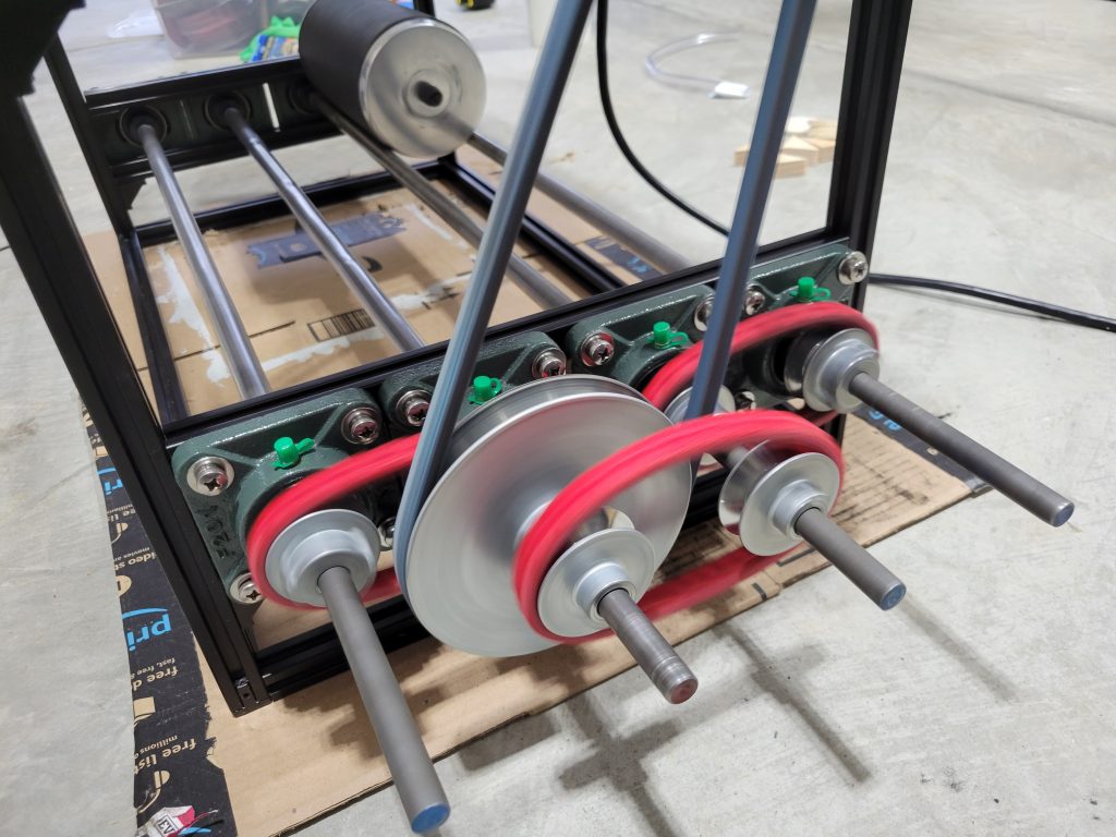 Metal roller rods and pulley drive components mounted in the custom rock tumbler frame.