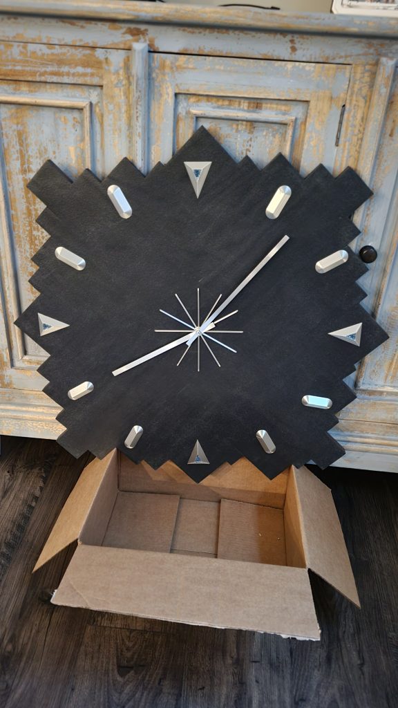 Finished abstract wall clock face showing metal markers, hands, and blue glass accents