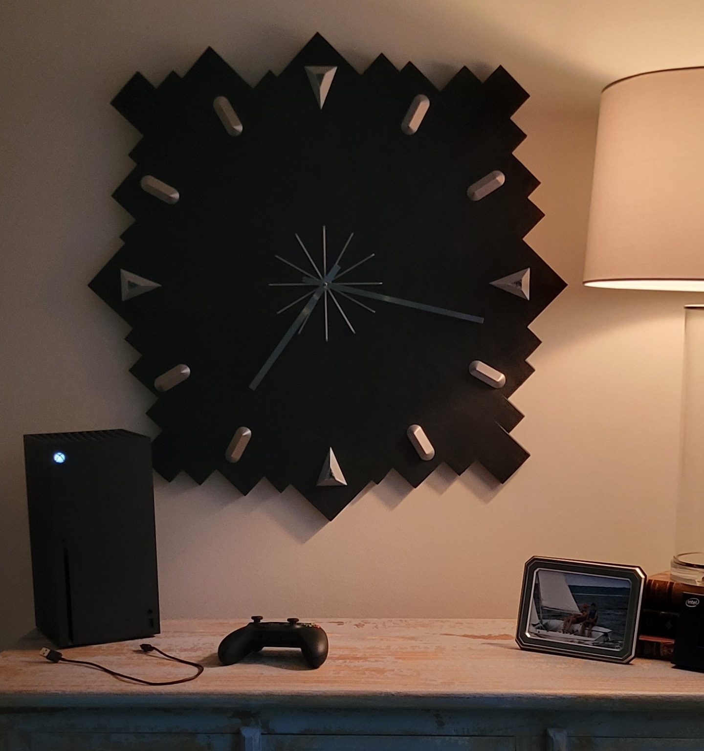 Close crop of the finished black geometric wall clock installed beside a warm lamp