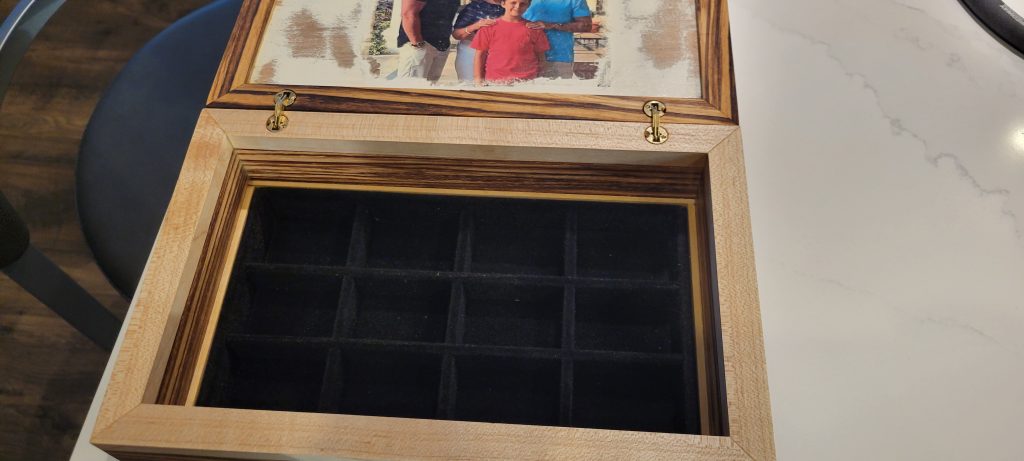 Open Zebrawood gift box showing barrel hinges and a black felt-lined jewelry insert