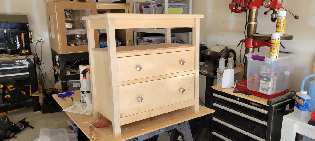 Unpainted nightstand assembled with drawers.