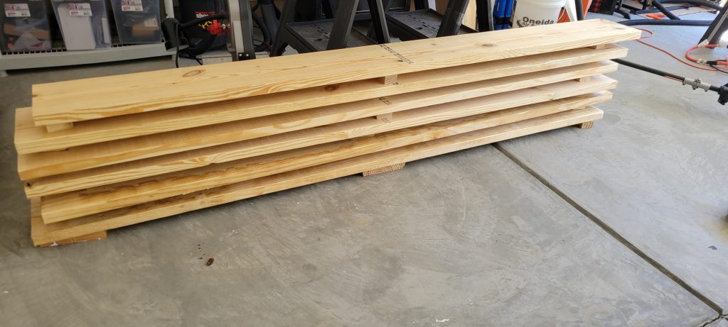 Pine boards stacked in the shop before the bench build