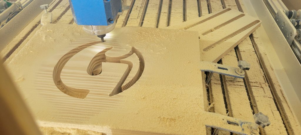 CNC router carving the G monogram into the bench backrest panel