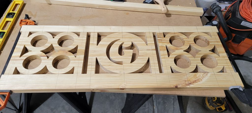 Bench backrest panel with G monogram and circle cutouts after CNC carving