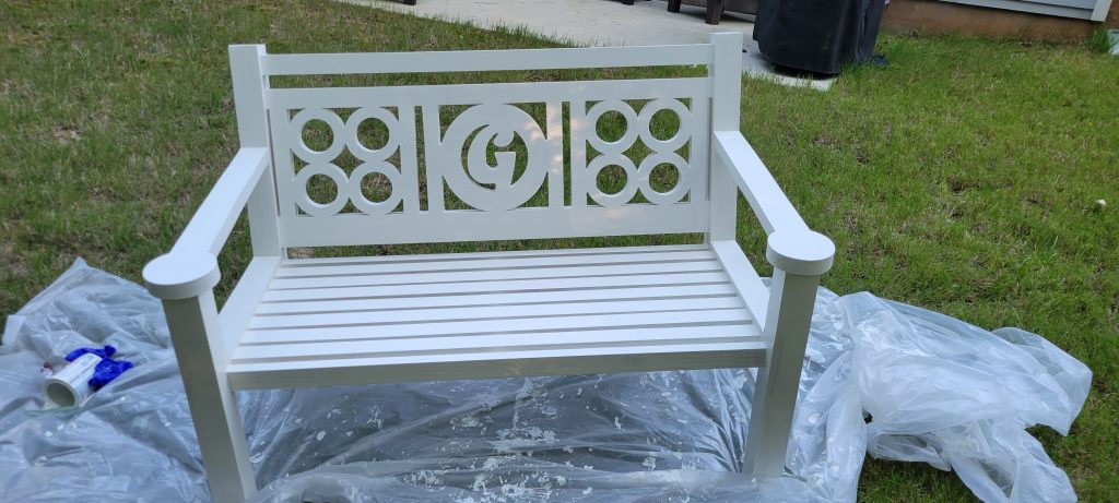 White painted front porch bench drying outside on a drop cloth