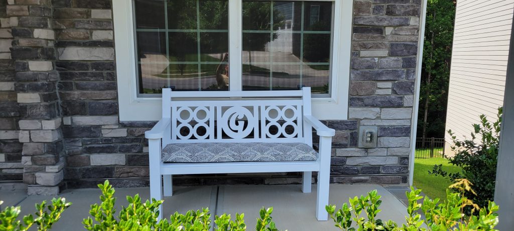 Finished white front porch bench with cushion installed below the front window