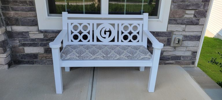 Finished white front porch bench with patterned cushion and G monogram backrest under the window