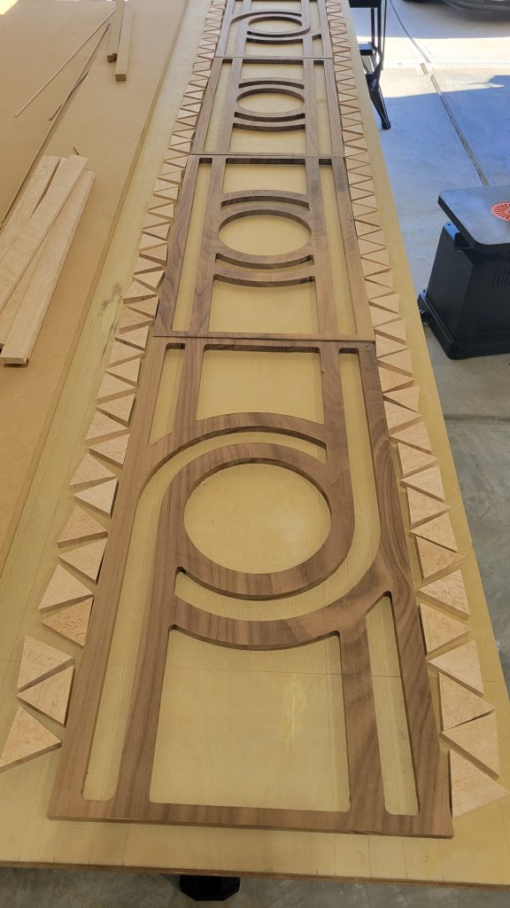 Full length plywood backer with walnut and birdseye maple inlay pieces laid out for the table top