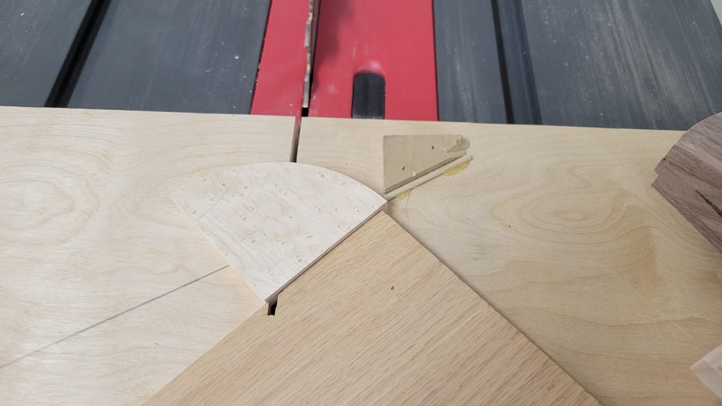 Small triangular inlay piece being cut at the table saw using a jig