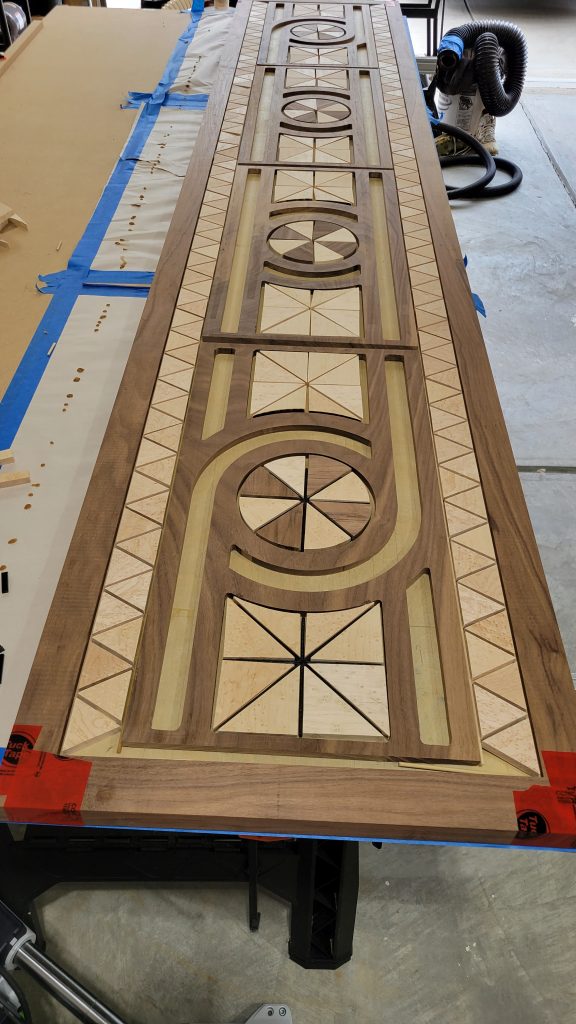 Long table top layout with walnut and birdseye maple inlays glued down and gaps left for black epoxy