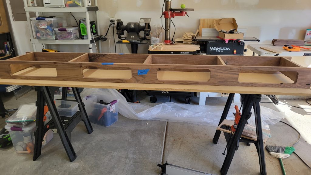 Long walnut table case in the shop with four drawer openings cut into the front