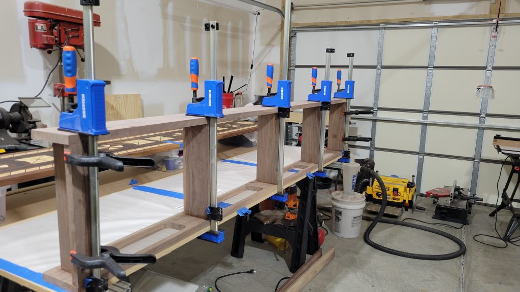 Eight foot walnut entry table frame clamped during assembly in the shop