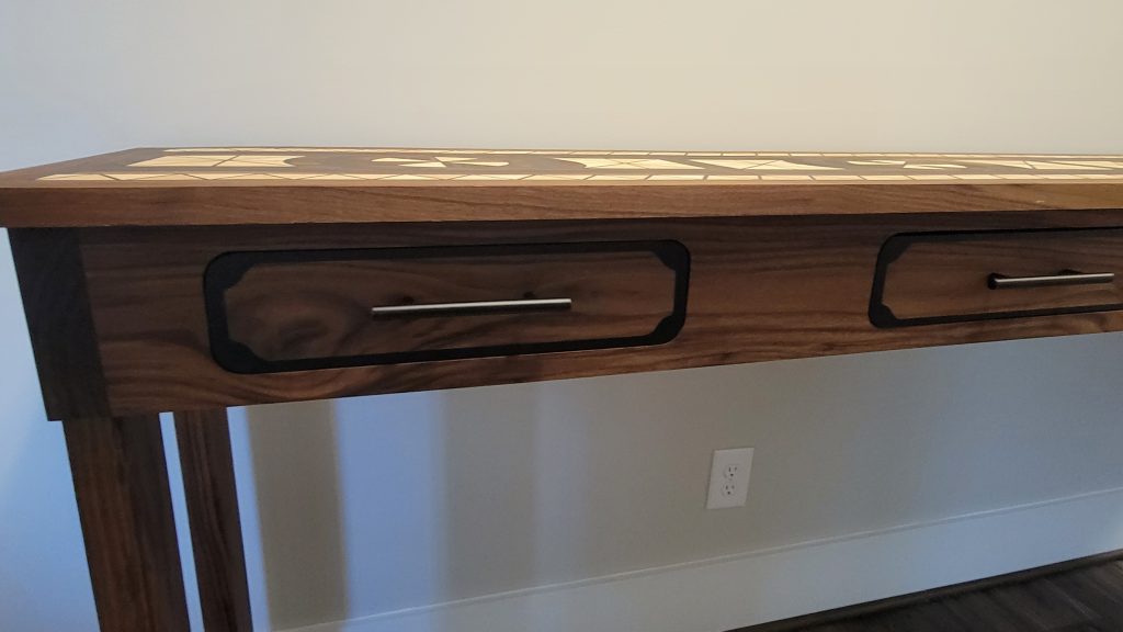 Close view of finished walnut drawer fronts with black epoxy borders and continuous grain