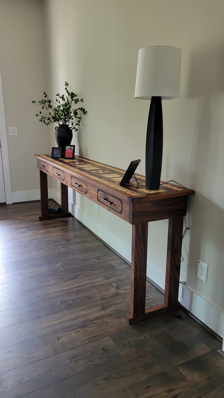 Staged finished walnut entry hall table with patterned top, lamp, and decor