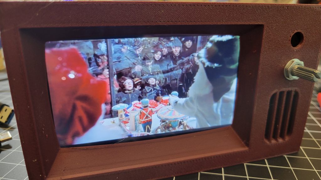 Close view of the mini TV front with LCD screen, speaker grille, and control knob visible