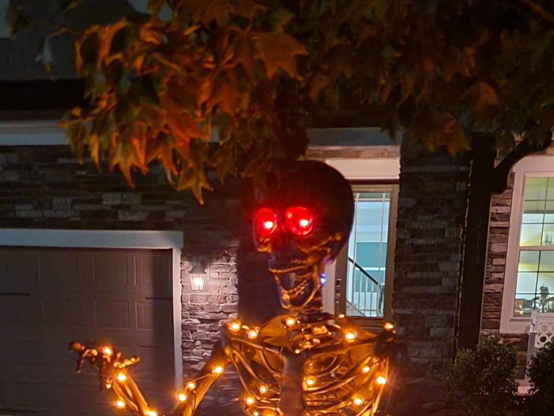 Head-focused crop of the matte black Halloween skeleton with red eyes and warm lights