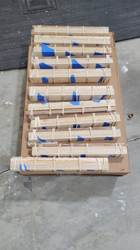 Chamfered plywood strips grouped with blue tape before glue-up for the patterned side table.