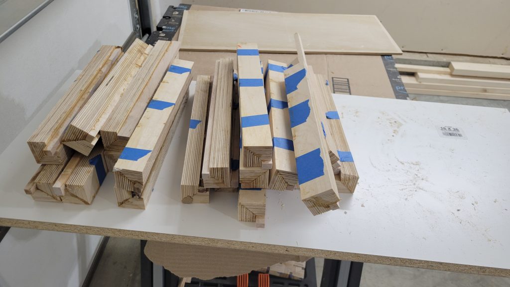 Long plywood strip blanks laid out on the shop table before adding walnut accents.