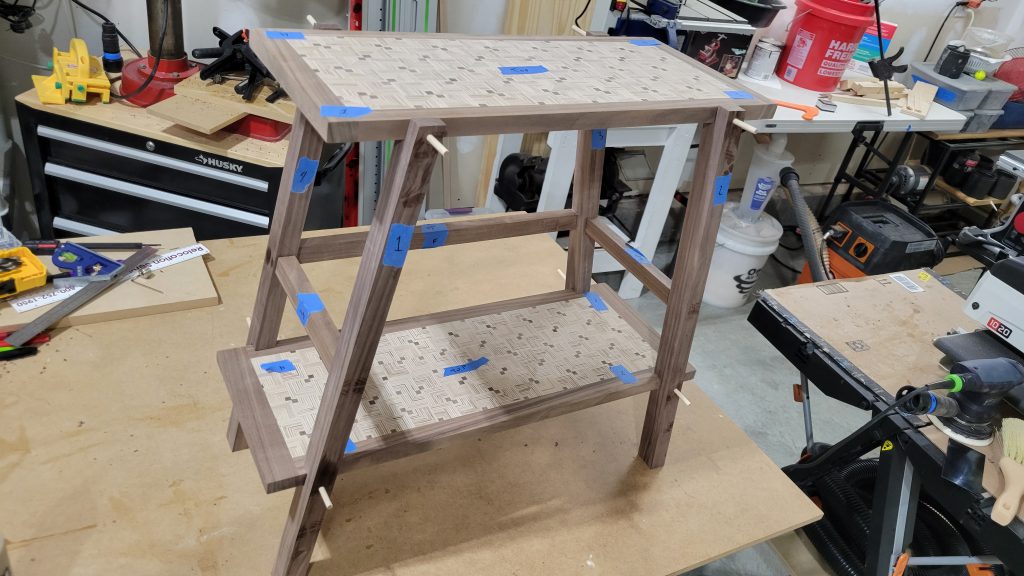 Walnut side table frame assembled with patterned plywood panels installed.