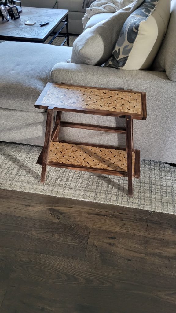 Finished patterned plywood side table viewed from above beside the sofa.