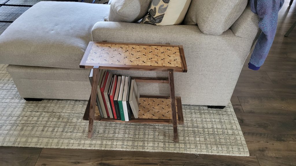 Finished patterned plywood side table with walnut frame in the room.
