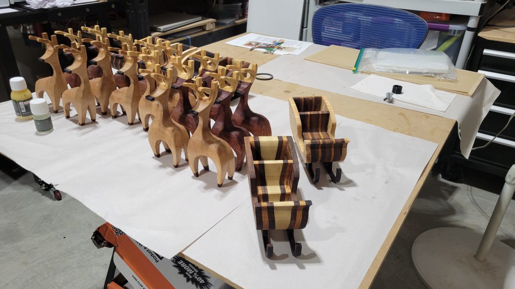 Finished set of hardwood reindeer and sleighs arranged on the work table.