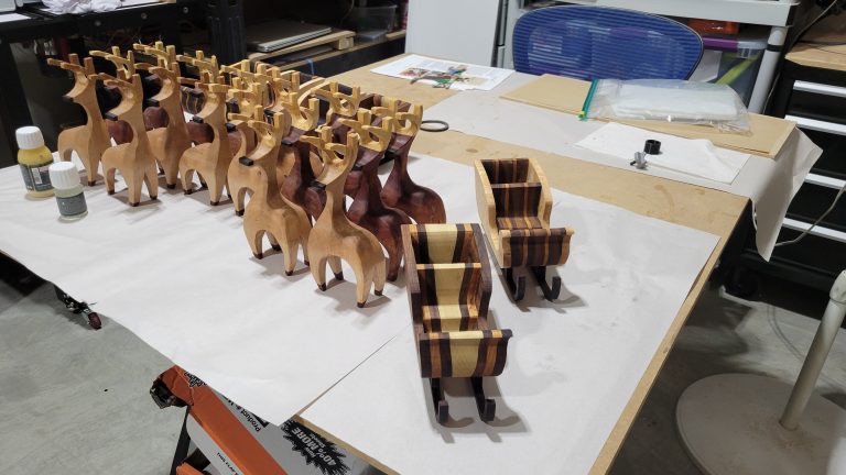 Finished set of hardwood reindeer and sleighs arranged on the work table.