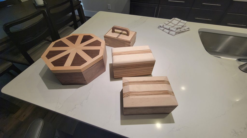 Several scrap wood box design tests arranged on a countertop.