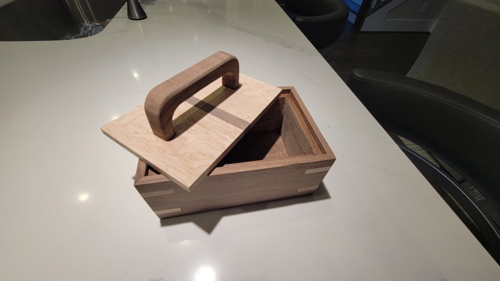 Open wooden box with the handled lid lifted to show the interior fit.