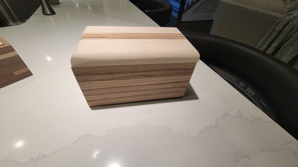 Small wooden box showing contrasting grain lines across the lid and body.