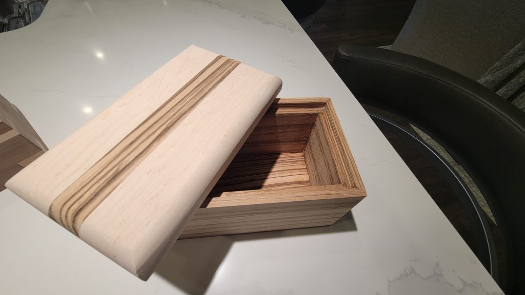 Open rectangular wooden box with a rounded lid shifted aside to reveal the interior.