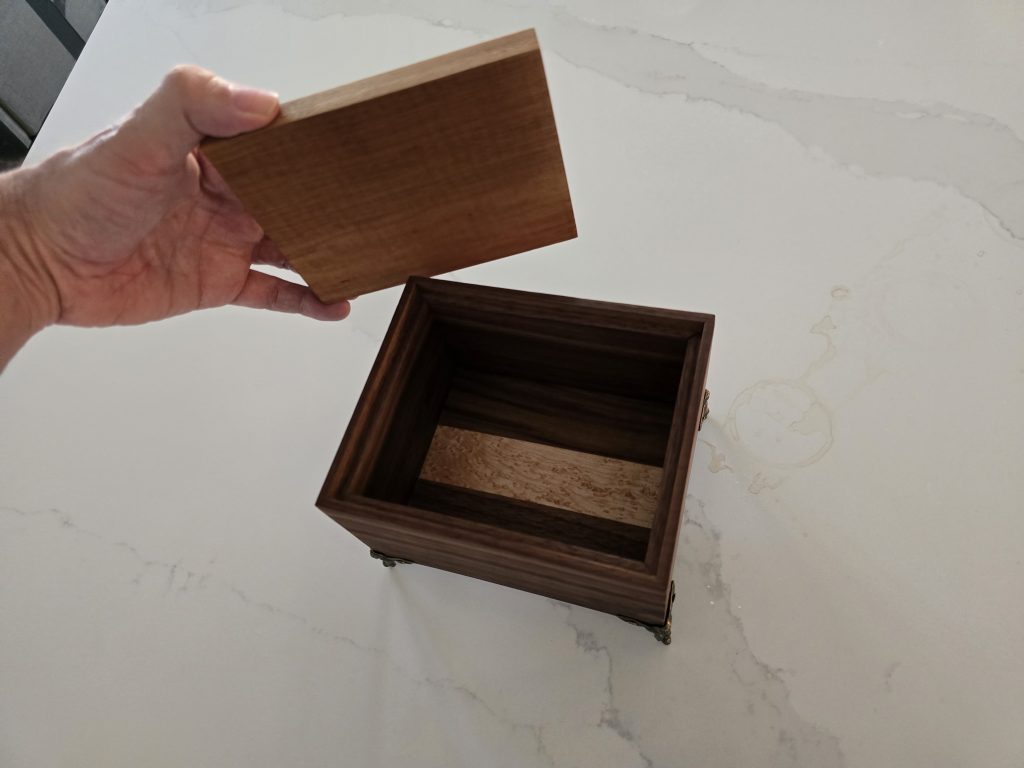 Open walnut gift box showing the birdseye maple stripe inside the base.