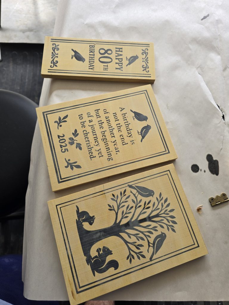 Yellowheart box panels laid out before assembly showing the birthday spine, quote panel, and front-cover engraving.