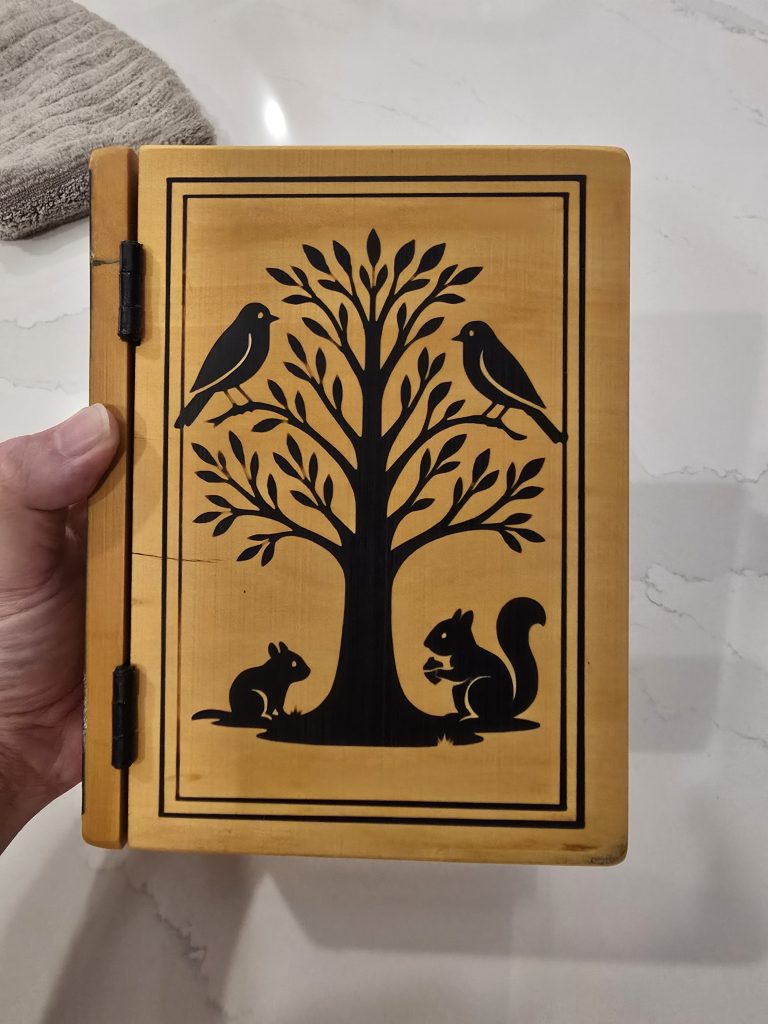 Finished yellowheart book-style 80th birthday box with black epoxy-filled tree engraving and black hinges.