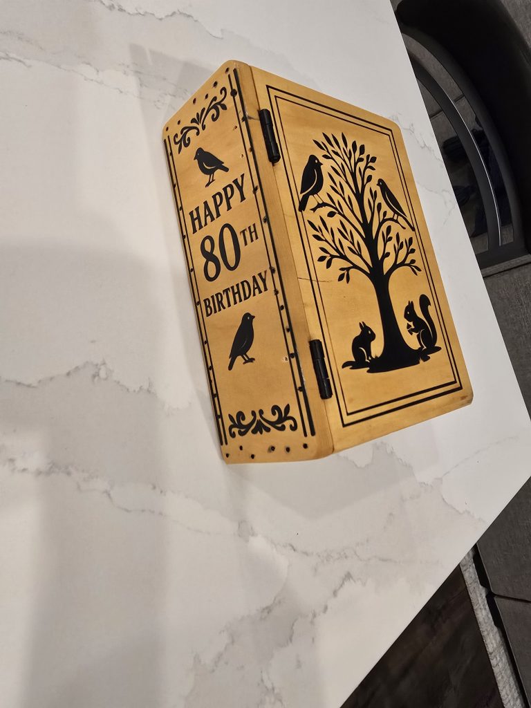 Finished book-style box showing the Happy 80th Birthday spine panel, black hinges, and engraved front cover.