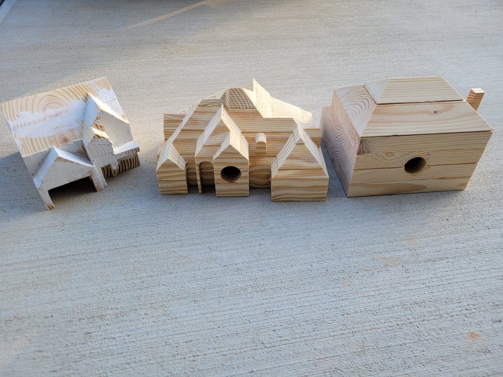 Unpainted wooden birdhouse body showing complex layered roof and facade