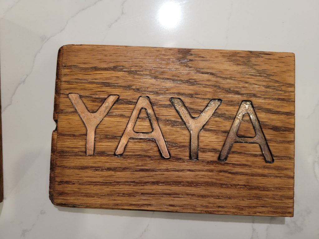 Close view of the wooden sliding lid with CNC-carved YaYa inlay and brass letters