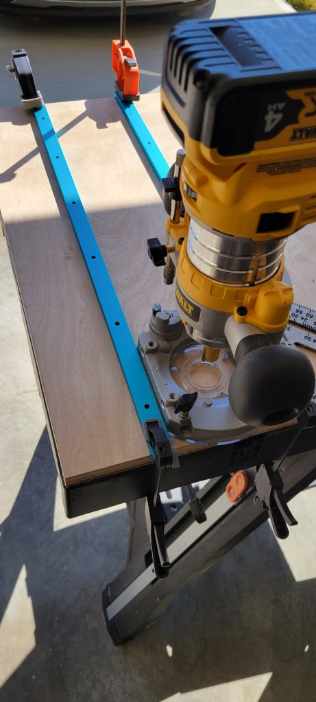 Router setup used to cut blue T-track slots in the sled base.