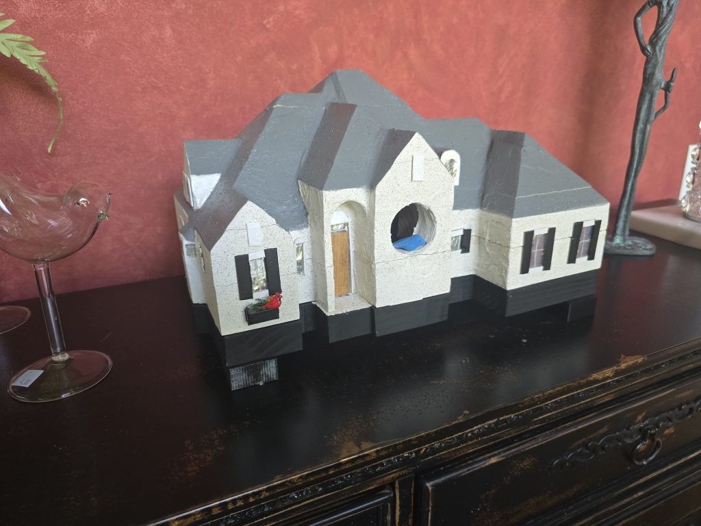 Finished custom birdhouse modeled after a white painted brick home