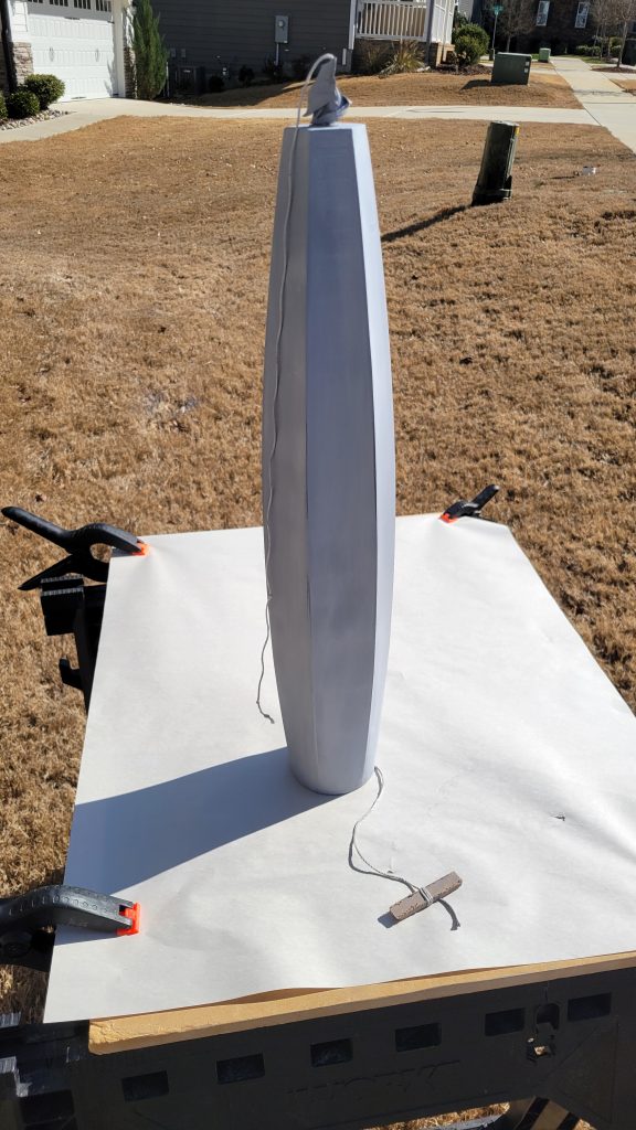 Primed lamp body set up outside for surface smoothing.