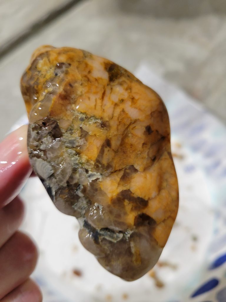 Yellow and translucent polished rocks held in hand after tumbling.