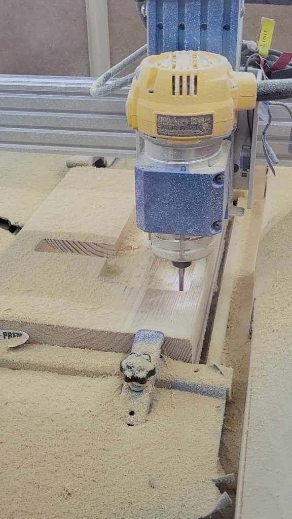 Still image of the CNC cutting the birdhouse shape from pine