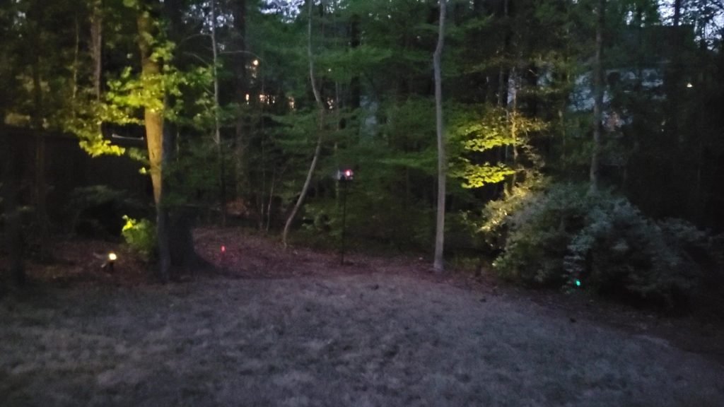 Finished birdhouse outside with the window glowing at dusk